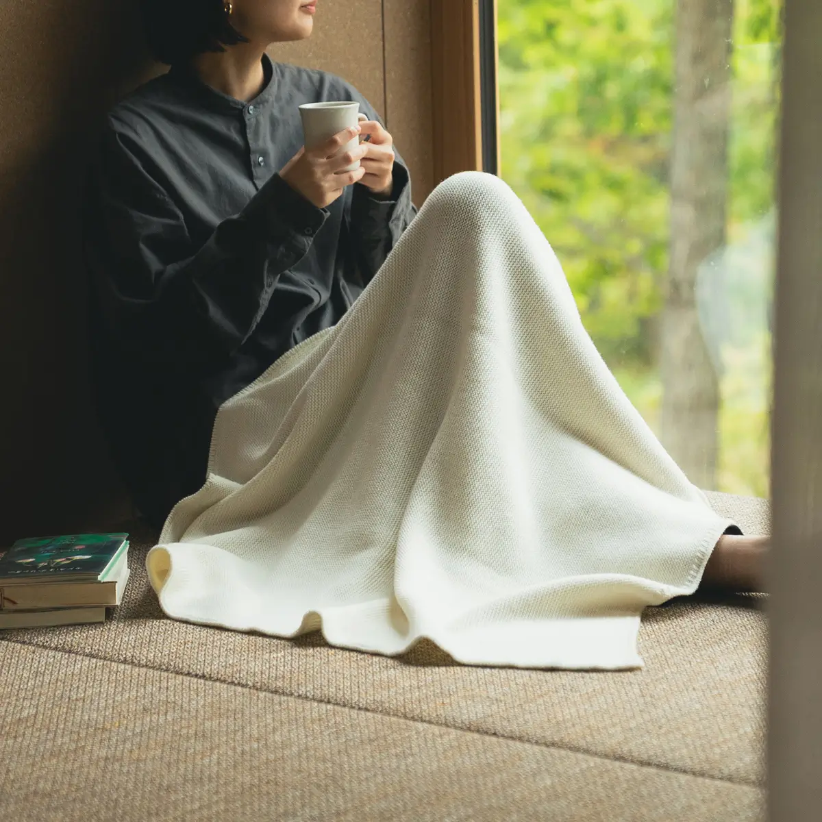 ブランケットを膝にかけてお茶を飲む人